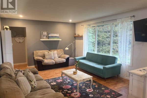 Living room with three sofas, a coffee table on a floral rug, and a large window with curtains. - 3203 Hwy 61 Highway, Thunder Bay Remote Area