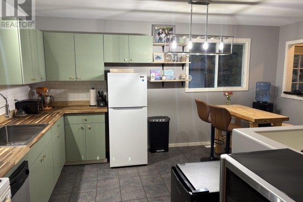Kitchen with light green cabinets, butcher block countertops, a white refrigerator, and a small island with two chairs. - 3203 Hwy 61 Highway, Thunder Bay Remote Area