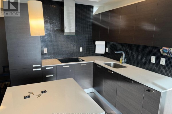 Close-up of a modern kitchen with dark cabinetry and black tile backsplash. - 3204 - 11 Bogert Avenue, Toronto