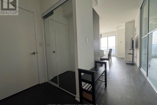 Hallway with white doors, mirrored closet, and dark wood flooring. - 3204 - 11 Bogert Avenue, Toronto