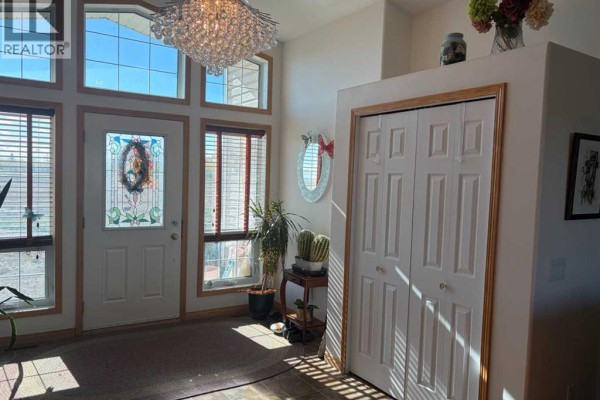 Interior entryway with a large crystal chandelier, tall windows with blinds, a decorative mirror, and a closet. - 32048 Twp Rd 812, Rural Fairview No  136, M D  Of