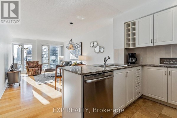 Kitchen area with white cabinets, granite countertops, double sink, and stainless steel dishwasher. - 3205 - 210 Victoria Street, Toronto