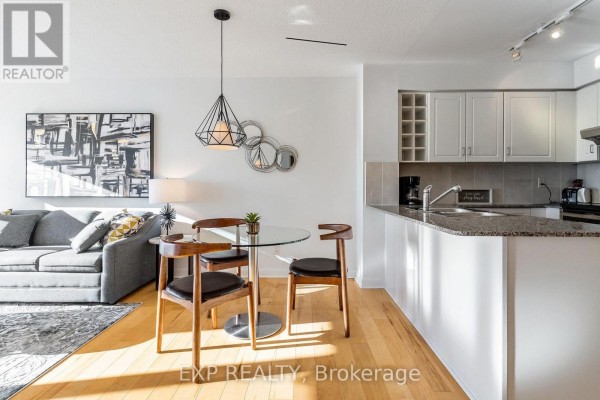 Dining area with glass-top table, wooden chairs, and adjacent living space. - 3205 - 210 Victoria Street, Toronto