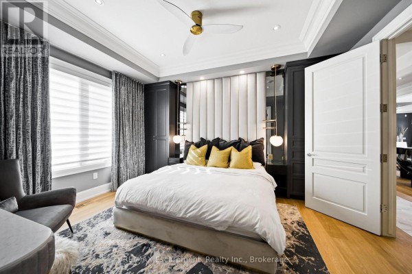 Primary bedroom with a king-size bed, upholstered headboard, dark closets, and a grey armchair. - 3205 Highpoint Court, Burlington