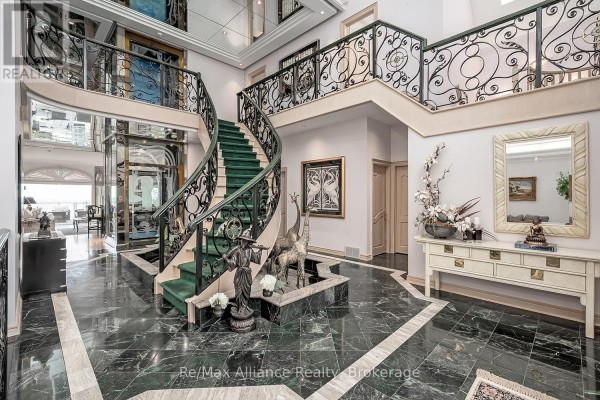 Grand foyer with a spiral staircase, green carpet, and marble flooring. - 3206 Shoreline Drive, Oakville