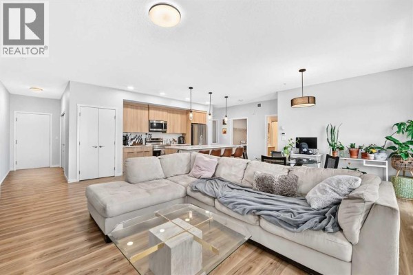 Hallway with light wood floors, white walls, and two closed white doors. - 3208, 220 Seton Grove Se, Calgary