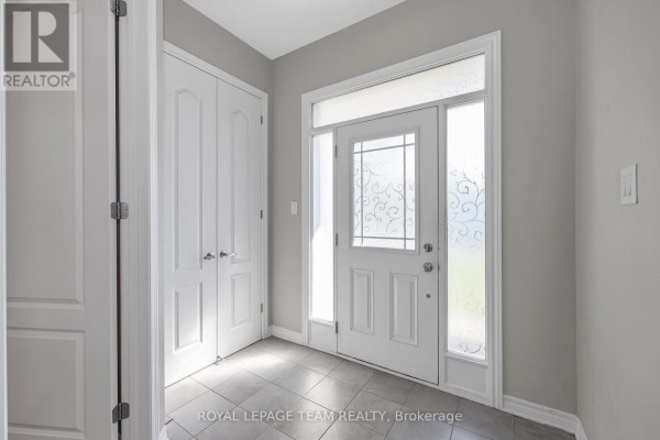 Interior foyer with a white front door, sidelights, frosted glass, and a double white closet. - 3209 Harvester Crescent, North Grenville