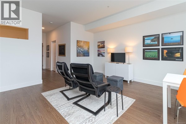 Living room featuring two chairs, TV stand, and artwork on the walls. - 321 515 Chatham St, Victoria