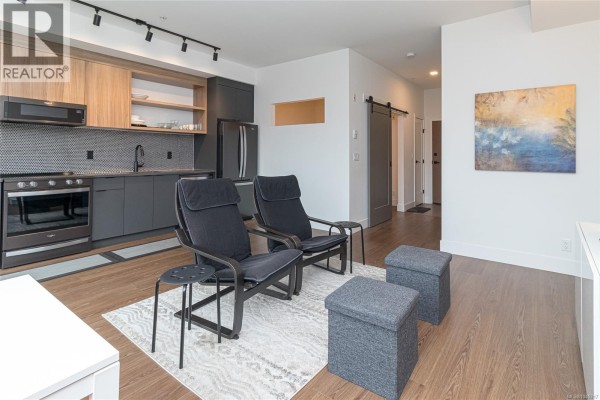 Open-concept living area with kitchen, seating, and modern appliances. - 321 515 Chatham St, Victoria