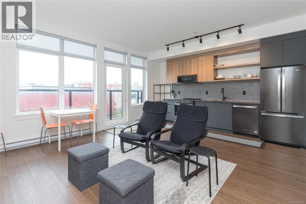 Bright kitchen and dining area with large windows, stainless steel appliances, and a dining table. - 321 515 Chatham St, Victoria