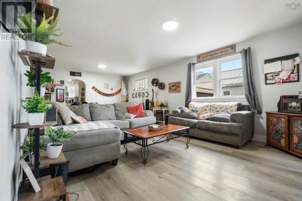 Living room with a sectional sofa, two armchairs, coffee table, and laminate flooring. - 321 Brunswick Street, Truro