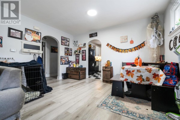 Combined living and dining area with arched doorways to the kitchen and Halloween decorations. - 321 Brunswick Street, Truro