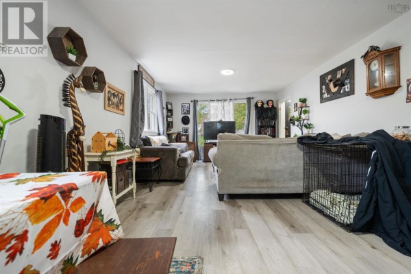 Wide view of the living room showing sofas, coffee table, dining area, and various decor. - 321 Brunswick Street, Truro