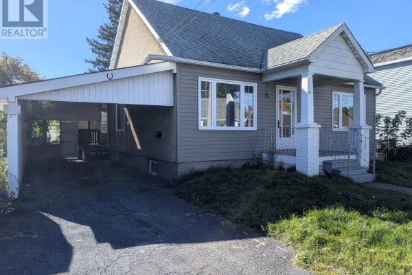 Side exterior view of a grey house with a covered carport on the left and white trim. - 321 Mclean Avenue, Cornwall