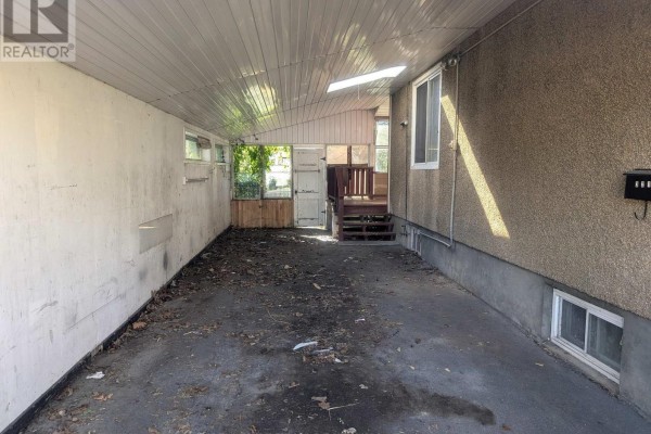 View inside a covered carport with concrete floor, unfinished walls, and a back door to a deck. - 321 Mclean Avenue, Cornwall