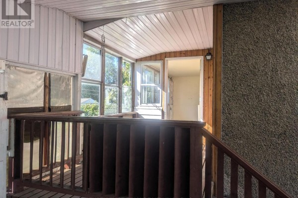 View of a wooden deck with dark brown railings, leading to a screened-in porch with large windows. - 321 Mclean Avenue, Cornwall