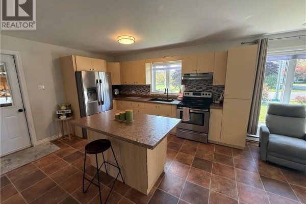 Kitchen with light wood cabinets, granite countertops, stainless steel appliances, and a large window. - 321 Route 134, Petit Rocher Nord
