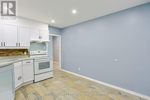 Kitchen with white cabinets, grey countertops, tiled backsplash, and white appliances. - 321 Salisbury Street, London East