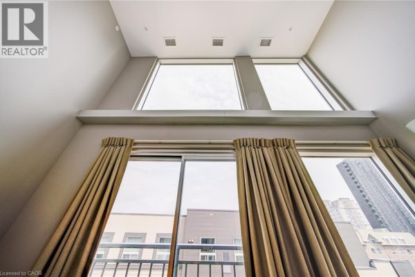 View looking up at tall windows and beige curtains in a modern apartment with grey walls. - 321 Spruce Street Unit# 710, Waterloo