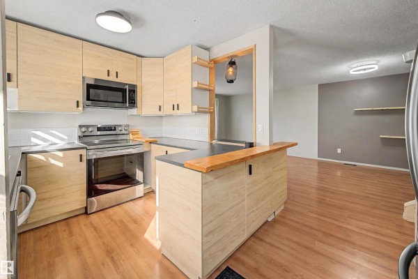 Close-up view of a U-shaped kitchen with light wood cabinets and stainless steel appliances. - 3211 71 St Nw, Edmonton