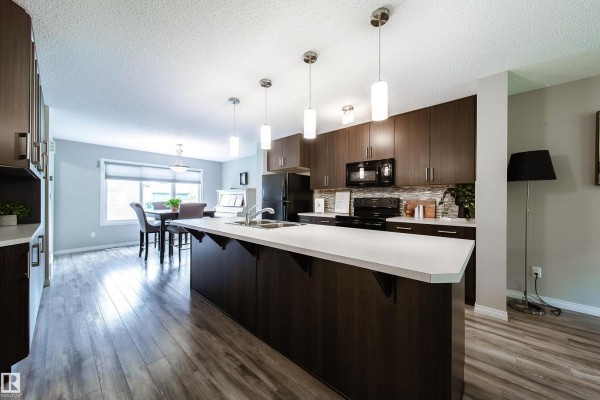 Kitchen with dark brown cabinets, white countertops, and a large island. - 3211 Cherry Cr Sw, Edmonton