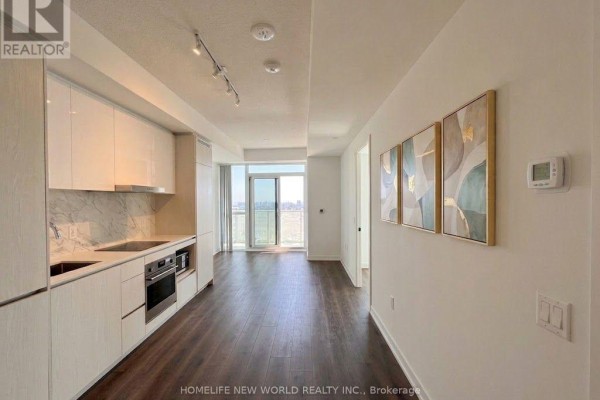 Open-concept living area and kitchen with white cabinets, stainless steel appliances, and dark wood floors. - 3212 - 28 Interchange Way, Vaughan