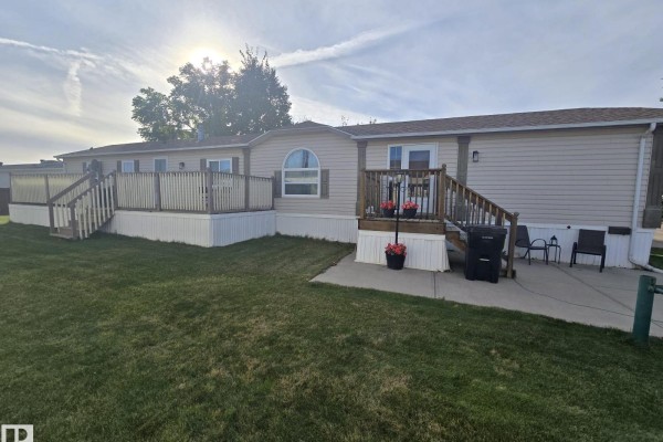 Rear view of a tan mobile home with a large wooden deck and two sets of stairs. - 3213 Lakewood Close Nw Nw, Edmonton