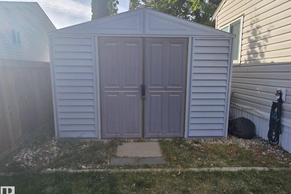 Exterior of a light gray storage shed with double doors on a gravel base. - 3213 Lakewood Close Nw Nw, Edmonton
