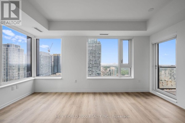 Bright room with panoramic city views through multiple windows and a glass door to a balcony. - 3214 - 101 Roehampton Avenue, Toronto