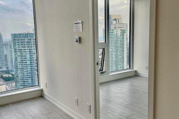 Room with large windows showing city view, door opening to another room. - 3215 - 55 Mercer Street, Toronto