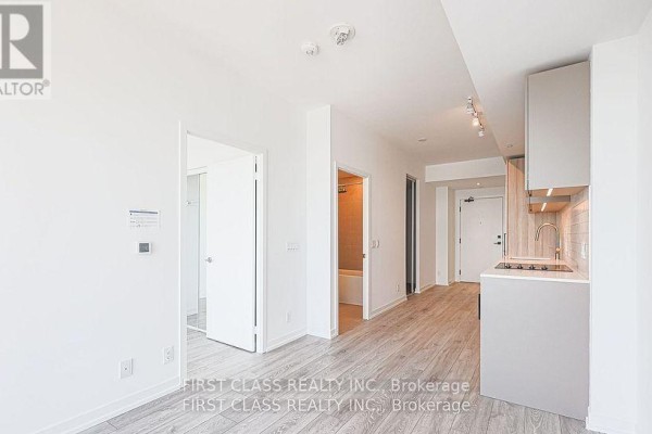 Living area showing entrance to bathroom and kitchen, with light grey floors. - 3215 - 55 Mercer Street, Toronto