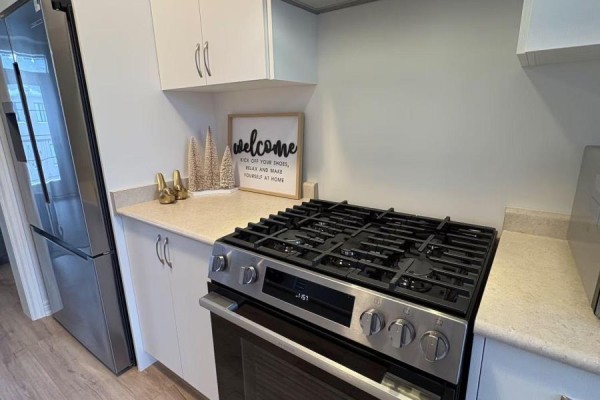 Gas range and stainless steel refrigerator in a kitchen with light wood floors. - 3216 Sixth Line, Oakville
