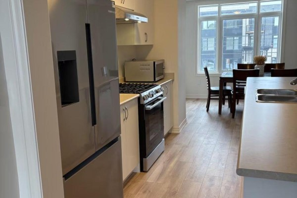 View of kitchen with stainless steel appliances, dining area, and large windows. - 3216 Sixth Line, Oakville