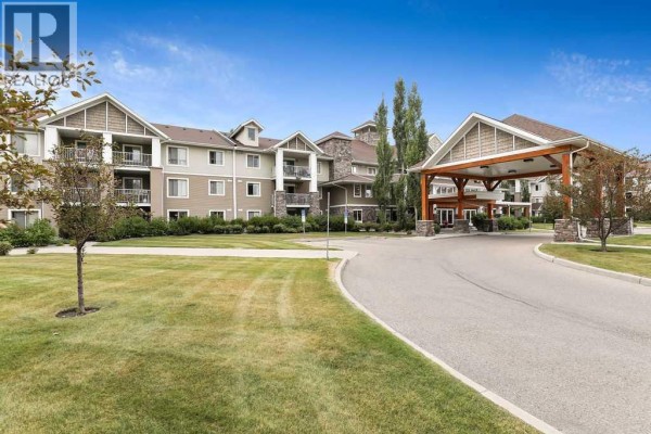 Kitchen with stainless steel appliances, white cabinets, and beige countertops. - 322, 428 Chaparral Ravine View Se, Calgary