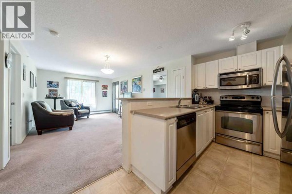Living room with beige carpet, two armchairs, and an open doorway to a bedroom. - 322, 428 Chaparral Ravine View Se, Calgary