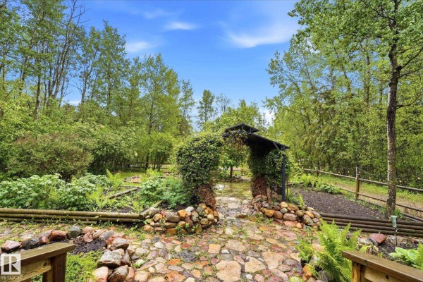 Stone patio area in a lush green garden with trees and shrubs. - #322 57230 Range Road 25, Rural Barrhead County