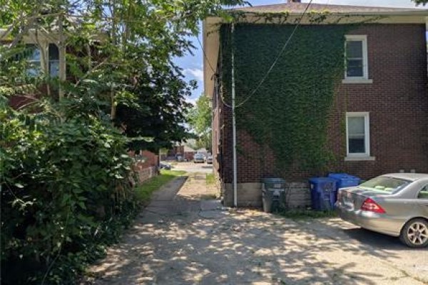 Side view of the duplex showing a narrow driveway and trees. - 322 Partington Unit# Upper, Windsor