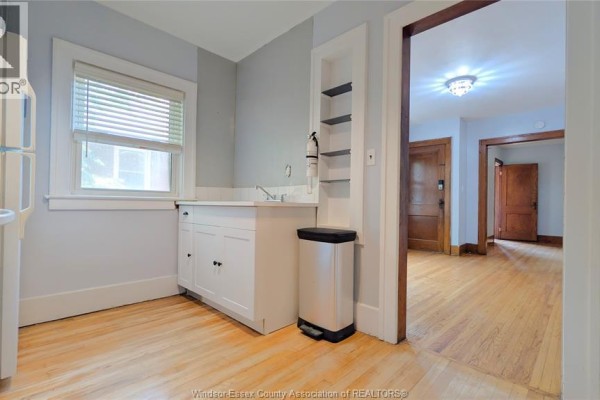 Small kitchen with white cabinetry, sink, and wood floors. - 322 Partington Unit# Upper, Windsor