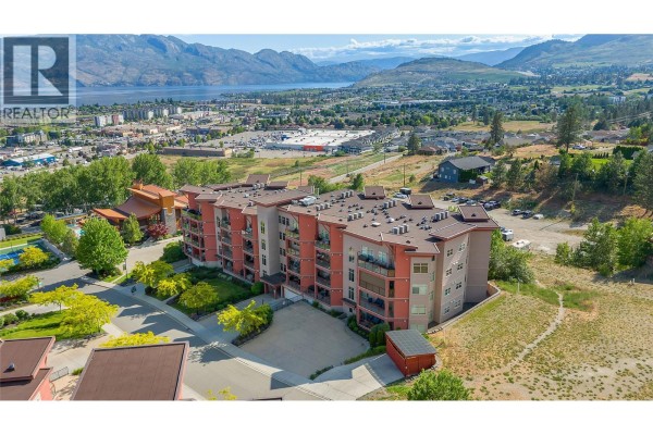 Aerial view of the apartment building complex with a lake and hills in the background. - 3220 Skyview Lane Unit# 302, West Kelowna