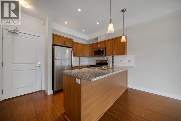 Kitchen with stainless steel appliances, granite countertop island, and wooden cabinets. - 3220 Skyview Lane Unit# 302, West Kelowna