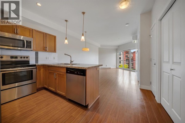 Open concept kitchen and living area with stainless steel appliances and large windows. - 3220 Skyview Lane Unit# 302, West Kelowna