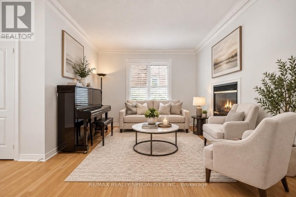 Living room with a fireplace, sofa, chairs, piano, coffee table, and large area rug. - 3225 Escada Drive, Mississauga