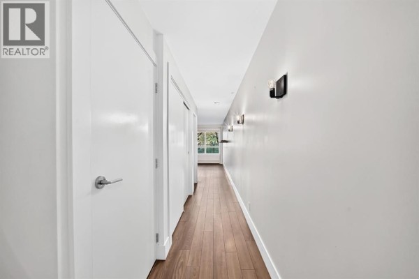Modern kitchen with dark cabinetry, stainless steel appliances, and patio doors opening to a balcony. - 323, 510 Edmonton Trail Ne, Calgary