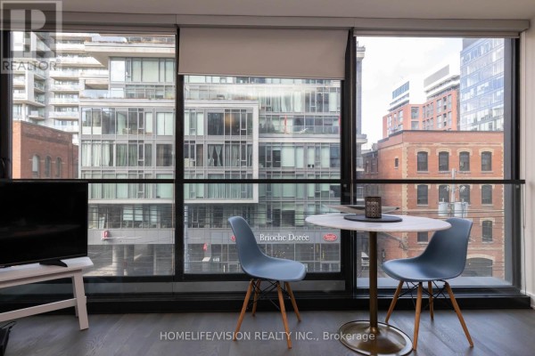 Dining nook with two blue chairs and a round table by floor-to-ceiling windows. - 323 - 629 King Street W, Toronto