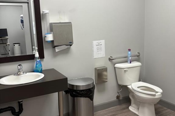 Commercial washroom with white toilet, sink vanity, mirror, and paper towel dispenser. - 323 Caradoc Street S, Strathroy Caradoc