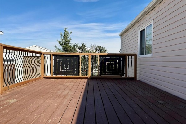 Close-up of the wooden deck with decorative metal panels and a sliding window on the mobile home. - 323 Glen Avenue, Brandon