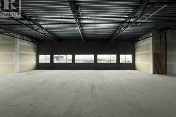 Wide view of unfinished commercial space with concrete floor, exposed metal ceiling, and drywall walls. - 3235, 6520 36 Street Ne, Calgary