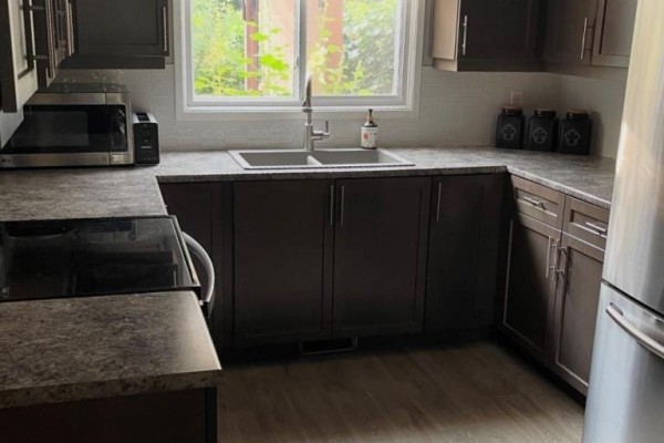 Kitchen with dark cabinets, a double sink, and a stainless steel microwave and stove. - 323a Wentworth Crescent, Thunder Bay