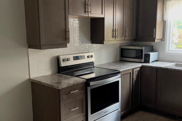 Dark wood kitchen cabinets, stainless steel range, tile backsplash, and granite countertops - 323a Wentworth Crescent Thunder Bay