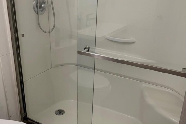 Glass-enclosed shower with seat and chrome fixtures, toilet, and wood-look flooring - 323a Wentworth Crescent Thunder Bay